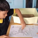 Children tracing Hindi letters with glue and sand at Sparkles International School
